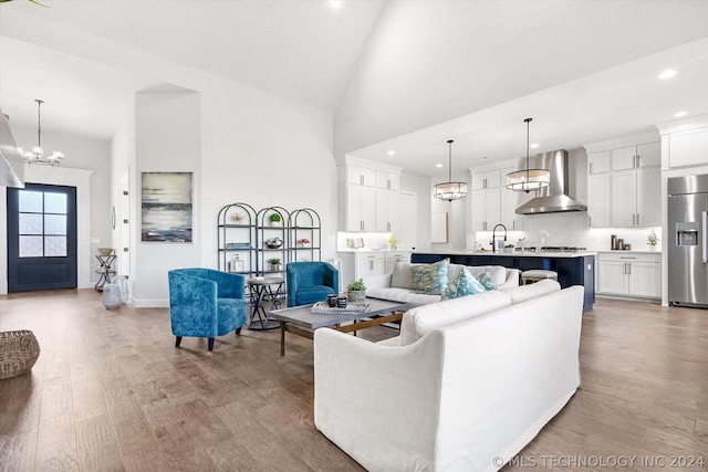 living room with sink, light hardwood / wood-style flooring, high vaulted ceiling, and a notable chandelier