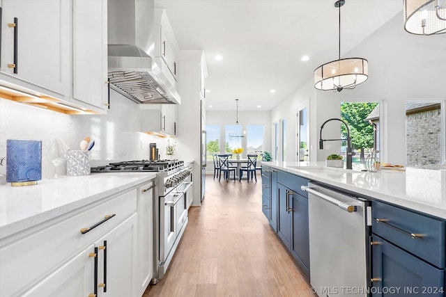 kitchen with white cabinets, stainless steel appliances, range hood, and pendant lighting