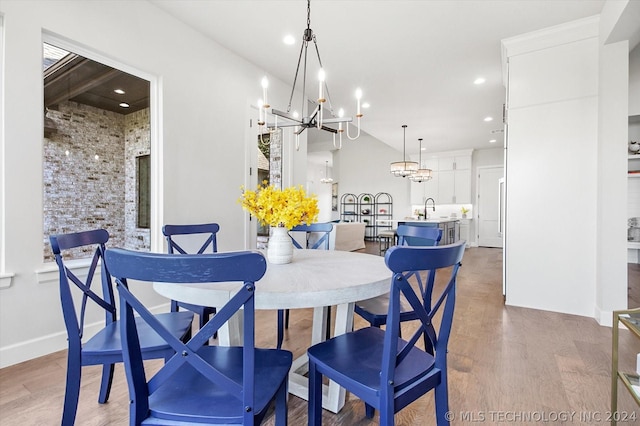 dining room featuring sink, hardwood / wood-style flooring, and an inviting chandelier