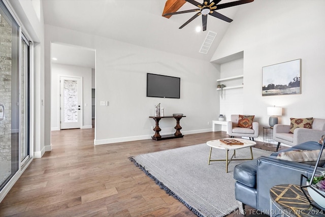 living room with ceiling fan, a wealth of natural light, wood-type flooring, and lofted ceiling