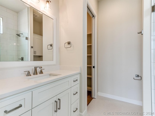 bathroom featuring tile patterned flooring, vanity, and tiled shower