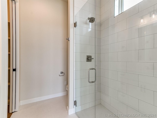 bathroom featuring tile patterned flooring, toilet, and a shower with shower door