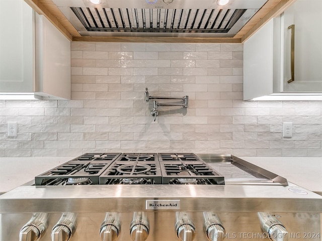 kitchen featuring extractor fan, tasteful backsplash, white cabinetry, stove, and stainless steel gas cooktop