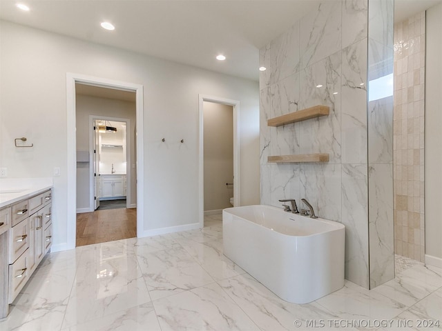 bathroom with toilet, vanity, a bath, and tile walls