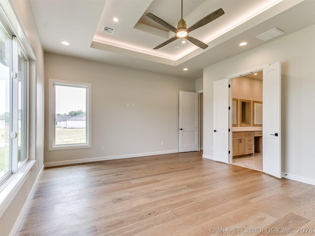 unfurnished room with ceiling fan, plenty of natural light, a raised ceiling, and light hardwood / wood-style flooring