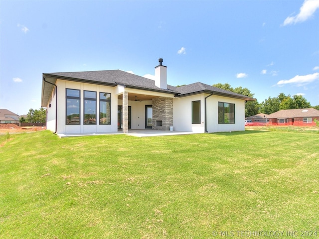 rear view of house featuring ceiling fan, a patio area, and a lawn