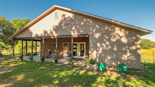 rear view of property featuring a yard, a patio, and french doors