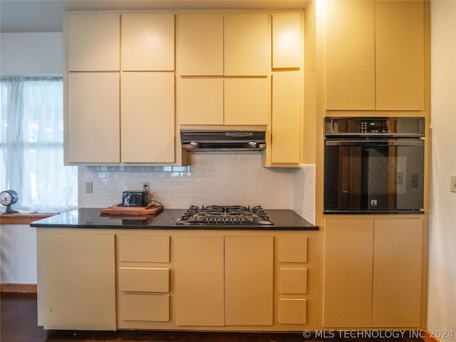 kitchen featuring oven, stainless steel gas cooktop, decorative backsplash, and range hood