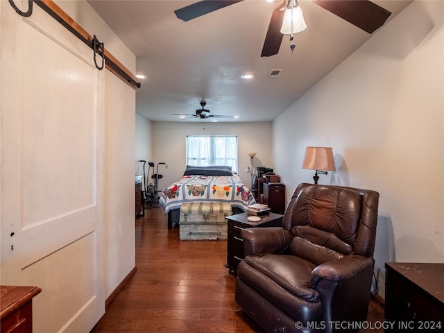 living room featuring a barn door, ceiling fan, and dark hardwood / wood-style floors