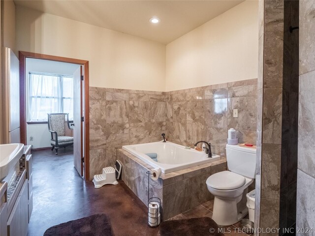 bathroom with toilet, concrete flooring, tile walls, and tiled bath