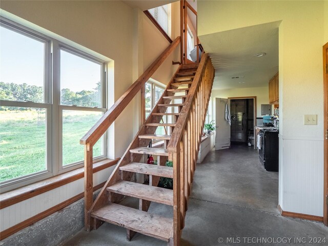 stairs featuring wood walls, concrete flooring, and a wealth of natural light