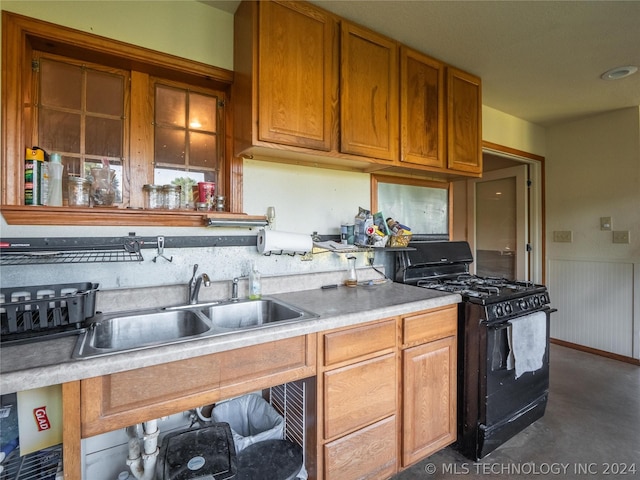 kitchen featuring sink, wooden walls, and black range with gas cooktop