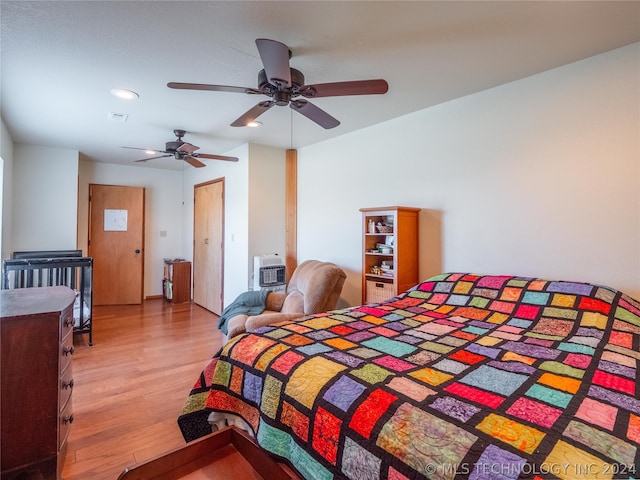 bedroom featuring heating unit, light hardwood / wood-style floors, and ceiling fan