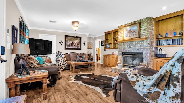 living room featuring light hardwood / wood-style floors, ornamental molding, and a brick fireplace