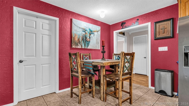 dining area with a textured ceiling and light tile patterned floors