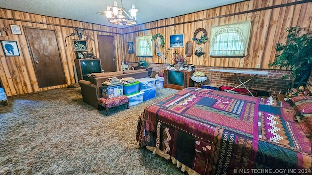 carpeted bedroom featuring wooden walls, a chandelier, and a textured ceiling