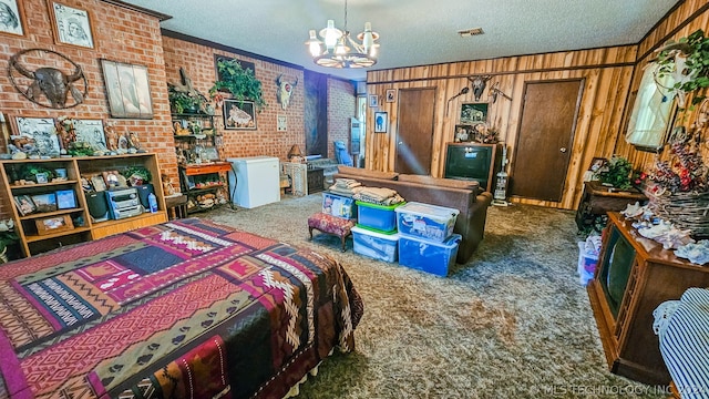 carpeted bedroom with ornamental molding, brick wall, a textured ceiling, wooden walls, and an inviting chandelier