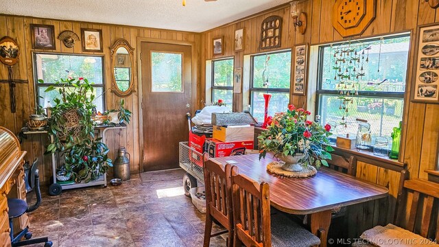 dining room with a textured ceiling and wooden walls