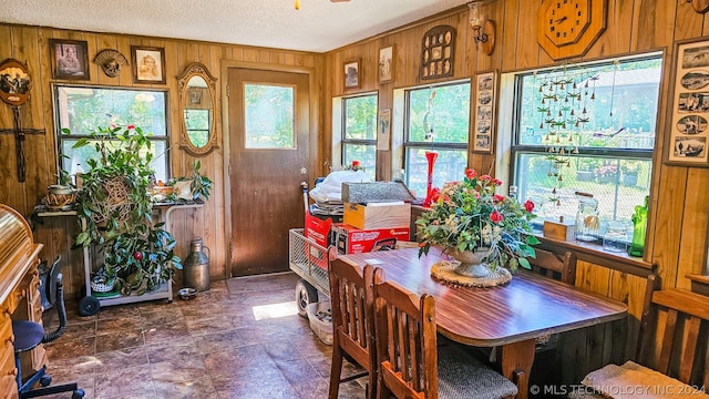 dining area with wood walls and a textured ceiling