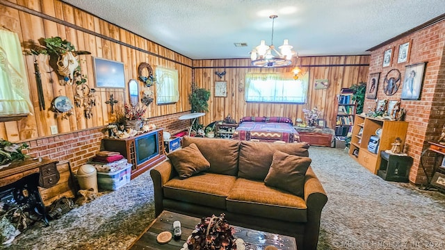 living room with carpet, brick wall, a textured ceiling, wooden walls, and a notable chandelier