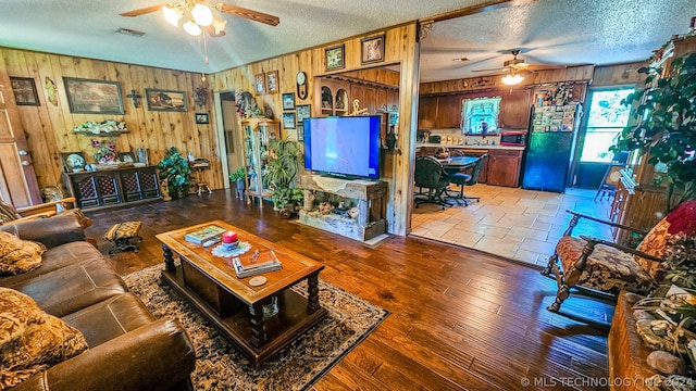 living room with hardwood / wood-style flooring, wood walls, and a textured ceiling