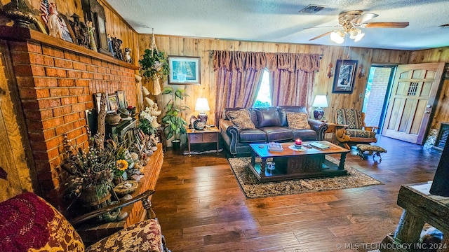 living room featuring dark hardwood / wood-style flooring, a textured ceiling, ceiling fan, and wood walls