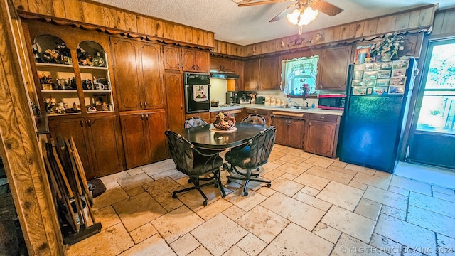 kitchen featuring ceiling fan, sink, a textured ceiling, stainless steel gas stovetop, and black oven