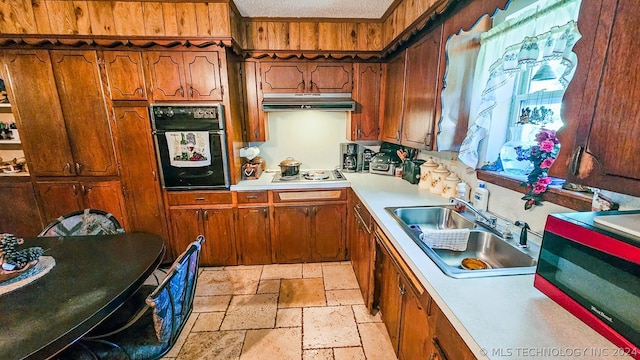 kitchen with light countertops, black oven, a sink, and under cabinet range hood