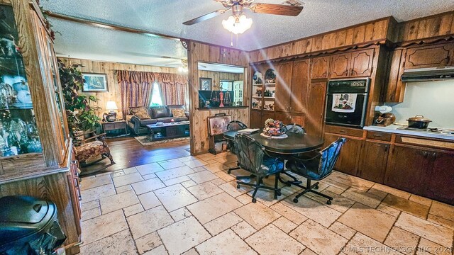 dining room with ceiling fan, a textured ceiling, and wooden walls