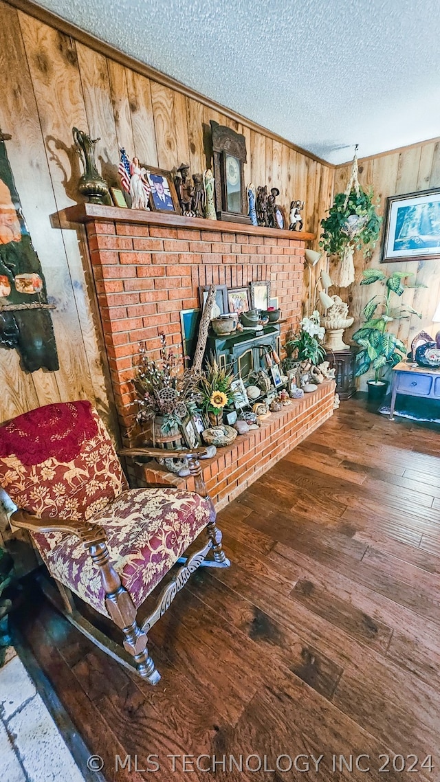 living area featuring a textured ceiling, hardwood / wood-style flooring, and wooden walls