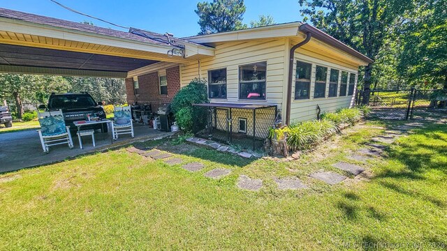 back of property with a lawn and a carport