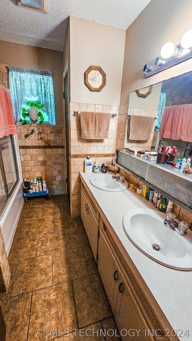 bathroom with a sink, a textured ceiling, and double vanity