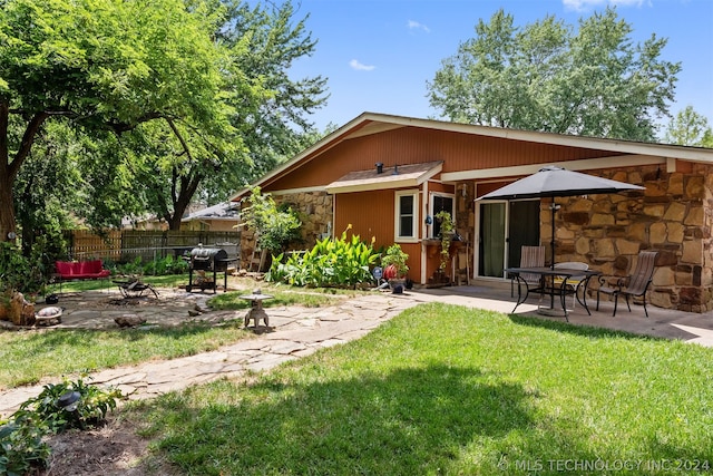 rear view of property with a lawn, a patio area, and an outdoor fire pit