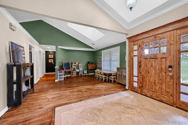 tiled foyer entrance with ornamental molding and vaulted ceiling with skylight