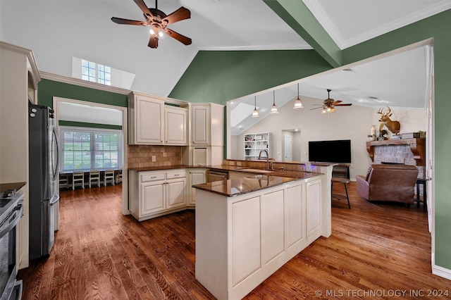 kitchen with kitchen peninsula, decorative backsplash, appliances with stainless steel finishes, ceiling fan, and sink