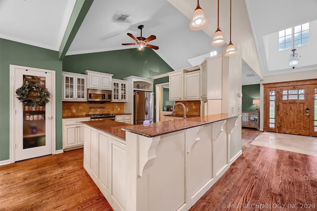 kitchen with decorative backsplash, stainless steel appliances, decorative light fixtures, dark stone countertops, and white cabinetry