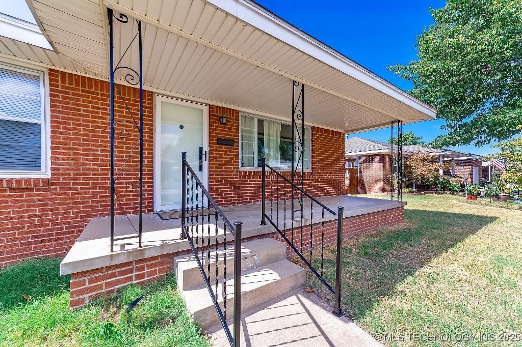 entrance to property featuring a yard and covered porch