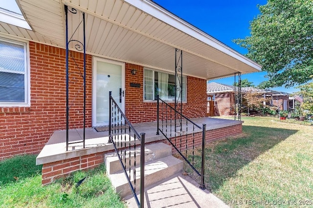 entrance to property featuring a yard and covered porch