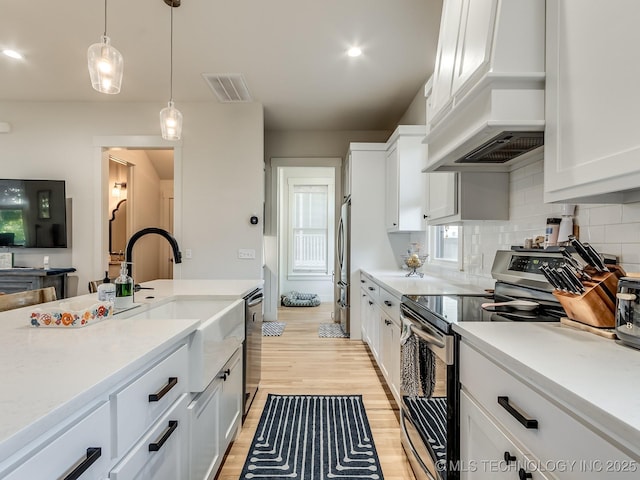75 Lower Green Way, Carlton Landing, OK 74432 - kitchen with stainless steel appliances, custom range hood, white cabinetry, light wood finished floors, and light countertops