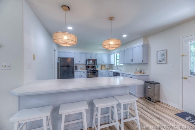 kitchen with black appliances, decorative light fixtures, tasteful backsplash, kitchen peninsula, and a breakfast bar area