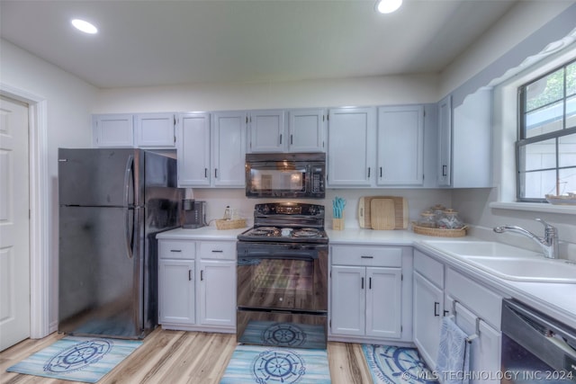 kitchen featuring black appliances, sink, and light hardwood / wood-style floors