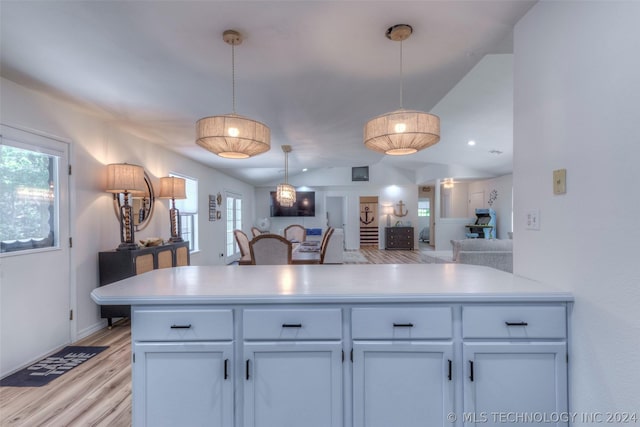 kitchen featuring vaulted ceiling, pendant lighting, white cabinets, and light wood-type flooring