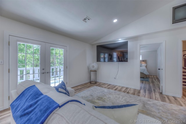 living room with lofted ceiling, light hardwood / wood-style floors, and french doors