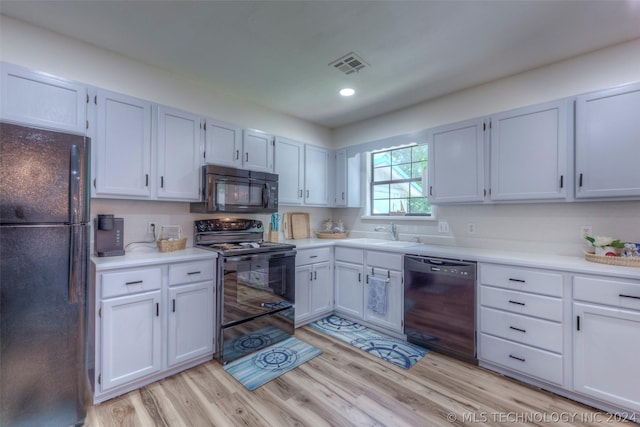 kitchen with light hardwood / wood-style floors, sink, white cabinets, and black appliances