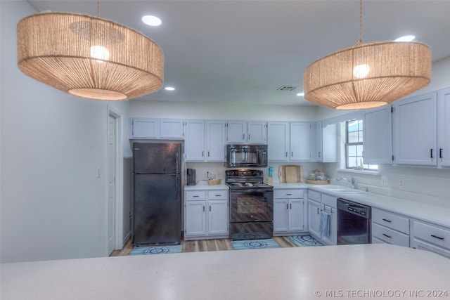 kitchen featuring black appliances, white cabinetry, light hardwood / wood-style floors, sink, and hanging light fixtures