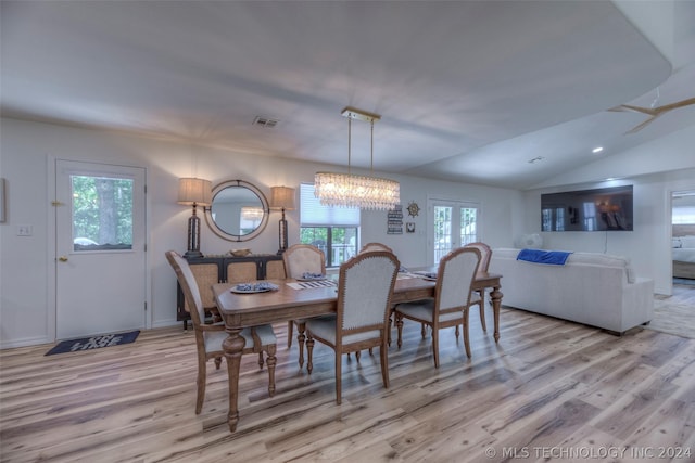 dining space with vaulted ceiling, a chandelier, and light hardwood / wood-style flooring