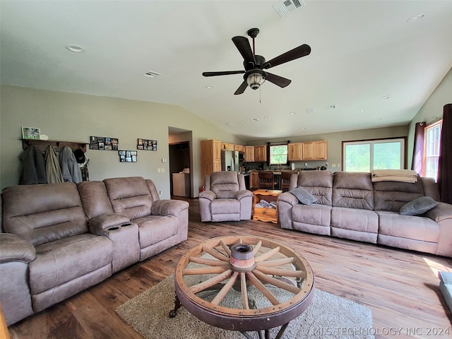 living room with ceiling fan, vaulted ceiling, and light hardwood / wood-style flooring