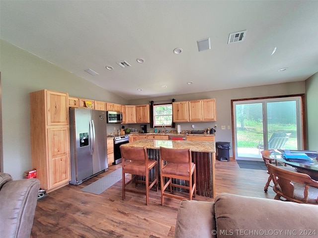 kitchen with light hardwood / wood-style floors, stainless steel appliances, vaulted ceiling, a center island, and a wealth of natural light