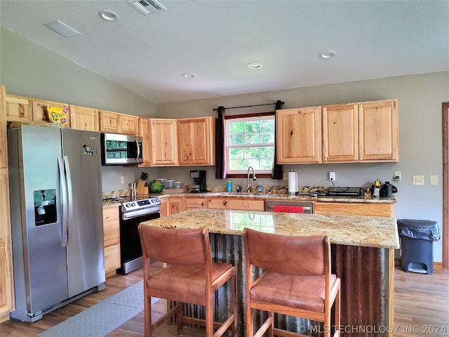 kitchen with stainless steel appliances, wood-type flooring, a kitchen island, sink, and lofted ceiling