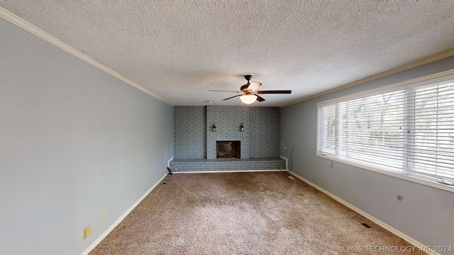 unfurnished living room with a brick fireplace, a textured ceiling, ornamental molding, carpet flooring, and ceiling fan